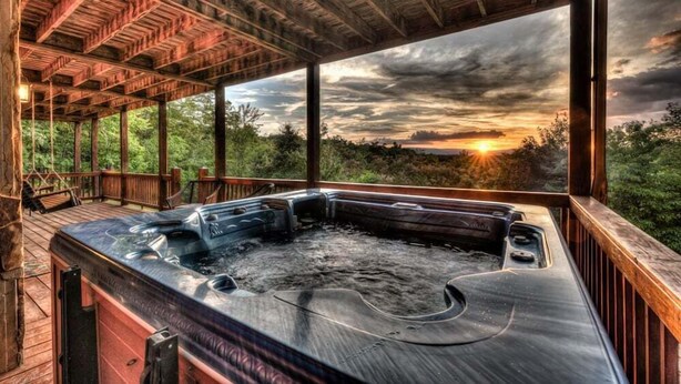 A hot tub in a wooden deck area with a view of the sunset. - Big Sky Retreat- Pet Friendly | Game Room | Hot Tub with Views (Blue Ridge)