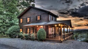 A two-story wooden house with a covered porch and a stone fireplace. - Big Sky Retreat- Pet Friendly | Game Room | Hot Tub with Views (Blue Ridge)