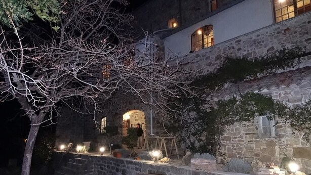 Un bâtiment en pierre doté d’une cour, de sièges en plein air et de fenêtres illuminées.
