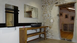Une salle de bain rustique avec un mur en pierre, un banc en bois et un grand miroir.