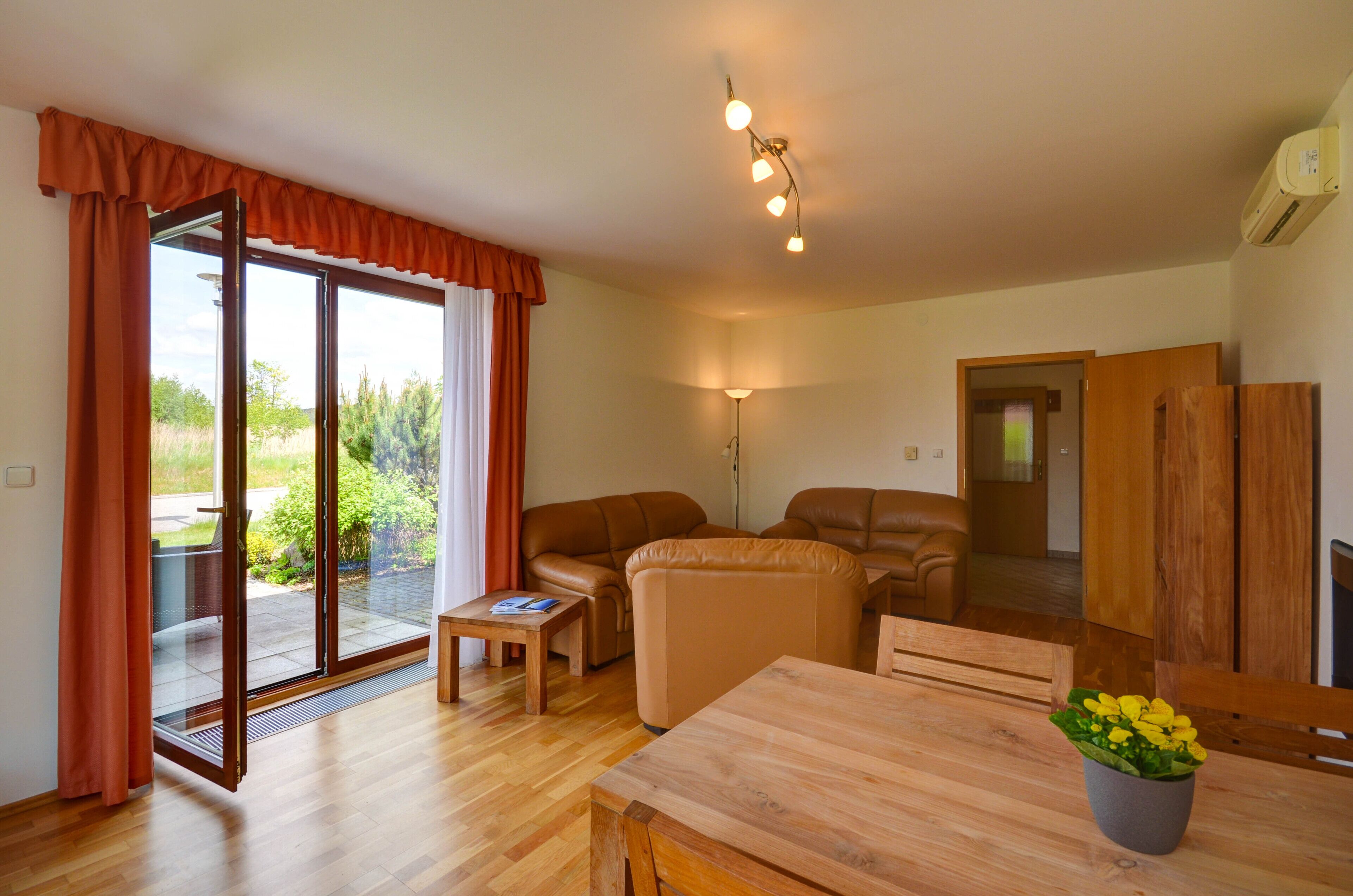 A spacious living area with a sliding glass door to a balcony, a wooden dining table, and a sofa.