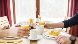 A breakfast setting with a wooden table, plates of food, and glasses of orange juice.