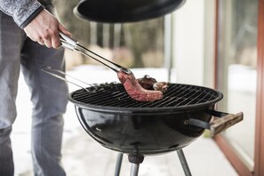 Una persona asando carne en una parrilla al aire libre.