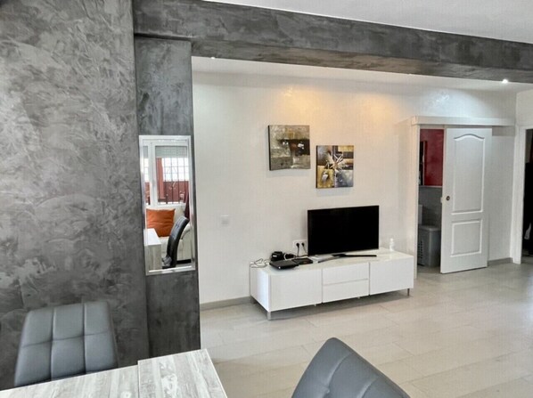 Una sala de estar moderna con un mueble blanco para entretenimiento, un televisor de pantalla plana y obras de arte en la pared.