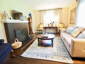 A living room with a fireplace, a sofa, a coffee table, and a dining table with chairs.