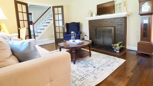 Una sala de estar con sofá, mesa de centro, chimenea y una escalera.