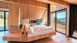 Une chambre moderne avec un plafond en pente, des meubles en bois intégrés, un grand lit et une vue sur l’extérieur.