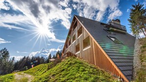 Une maison moderne avec un toit en pente, de grandes fenêtres et une terrasse en bois.