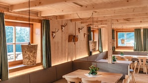 Un intérieur en bois comprenant un coin repas, des bancs et une fenêtre avec des rideaux.