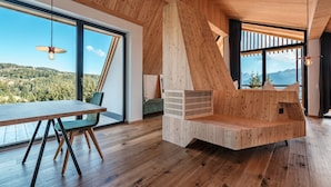 Un intérieur moderne avec une table à manger en bois, une chaise verte et un banc intégré offrant une vue sur l’extérieur.
