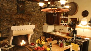 Una cocina rústica con pared de piedra, mostrador de madera y horno de leña.