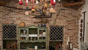 Un comedor rústico con una gran mesa de madera, lámpara colgante y paredes de ladrillo.