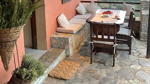 Un rincón al aire libre acogedor con escalones de piedra, una mesa con fruteros y vistas al paisaje.