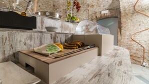 A rustic kitchen with a wooden countertop, a built-in bench, and a hanging fruit rack. - Hotel Cascina Fossata & Residence (Turin)