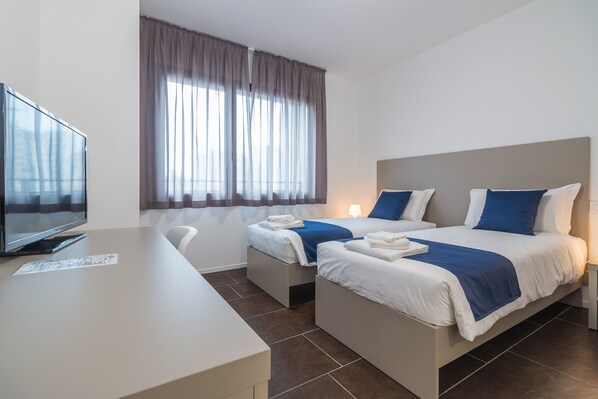 A hotel room with two beds, a desk, and a TV. - Hotel Cascina Fossata & Residence (Turin)