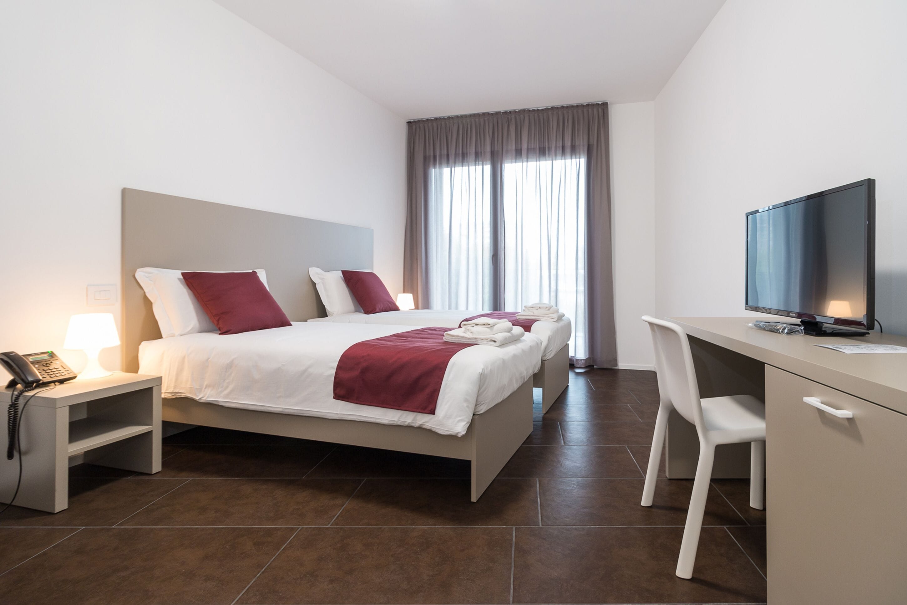 Une chambre d’hôtel équipée d’un lit, d’un bureau, d’une chaise, d’une télévision et d’un téléphone.
