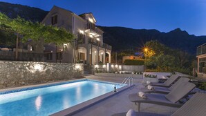A pool area with lounge chairs and a stone wall. - Apartments Mezini 11 (Kotor)