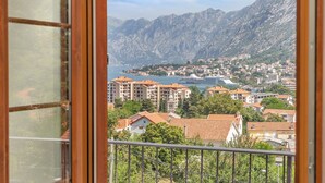 A view from a balcony overlooking a coastal town with mountains in the background. - Apartments Mezini 11 (Kotor)