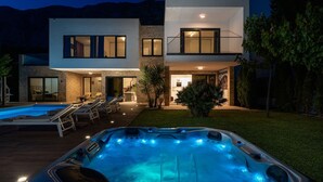 A modern two-story house with a swimming pool and hot tub.