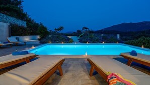 A swimming pool with lounge chairs and a slide, surrounded by greenery and mountains in the background. - Villa Belina: 4 ensuite bedrooms, game room, heated pool, sauna & gym (Gata)