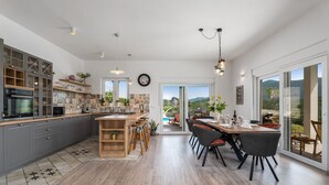 A modern kitchen with grey cabinets, a wooden island, and a dining area with a large table and chairs. - Villa Belina: 4 ensuite bedrooms, game room, heated pool, sauna & gym (Gata)