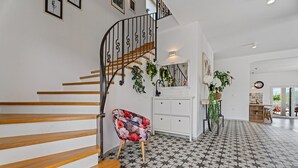 A staircase with wooden steps and a metal railing, a white cabinet with drawers, a floral chair, and a tiled floor with a star pattern. - Villa Belina: 4 ensuite bedrooms, game room, heated pool, sauna & gym (Gata)