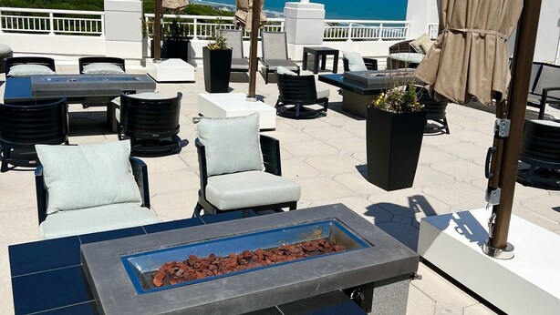 Une terrasse sur le toit avec des sièges extérieurs, un foyer et une vue sur l’océan.