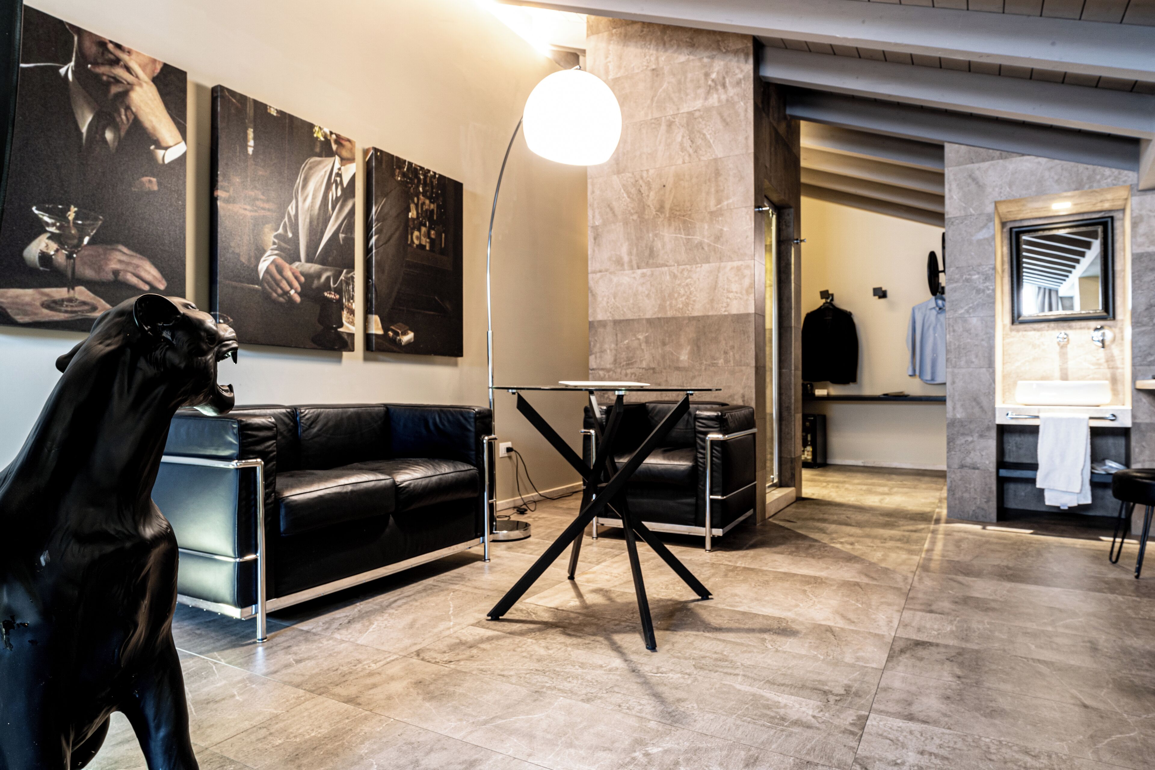 A modern interior with a black leather sofa, a black metal table, and a large floor lamp.