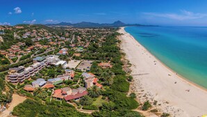 An aerial view of a coastal town with a long sandy beach, dense residential area, and a clear blue sea. - Neko Boutique Hotel (Cagliari)