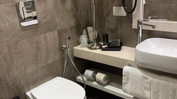 A modern bathroom with a toilet, bidet, vanity with a sink, and a towel rack.