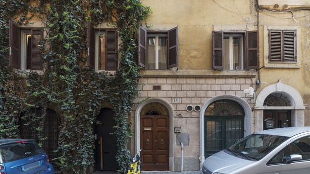 A narrow street with a building featuring a brown door and arched windows. - Fori Imperiali Elegant Apartment (Rome)