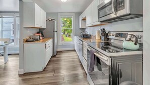 A modern kitchen with white cabinets, a stainless steel range, and a built-in oven. - Shortstop Apt 1 - All Star Baseball Rentals (Oneonta)