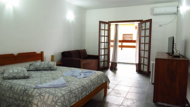 A bedroom with a bed, a wooden desk, a chair, and a sofa.