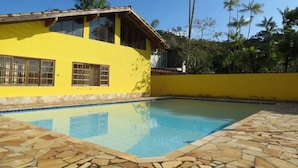 A yellow building with a swimming pool and stone-tiled deck.