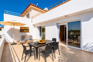 Une terrasse avec une table, des chaises et un parasol.