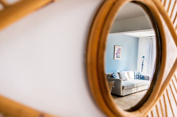 Ein Zimmer mit Spiegel, der einen Wohnbereich, eine Couch und eine Lampe reflektiert.