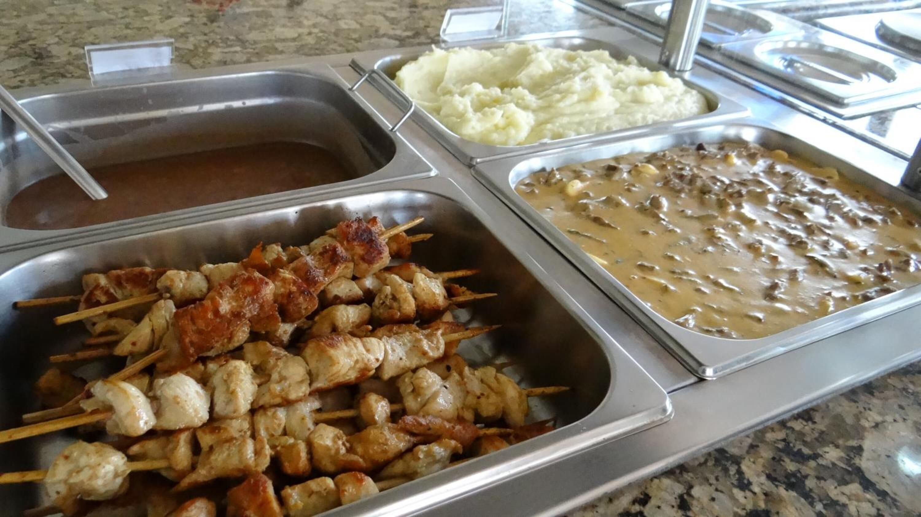 Een buffet met spiezen, aardappelpuree en een romige saus.