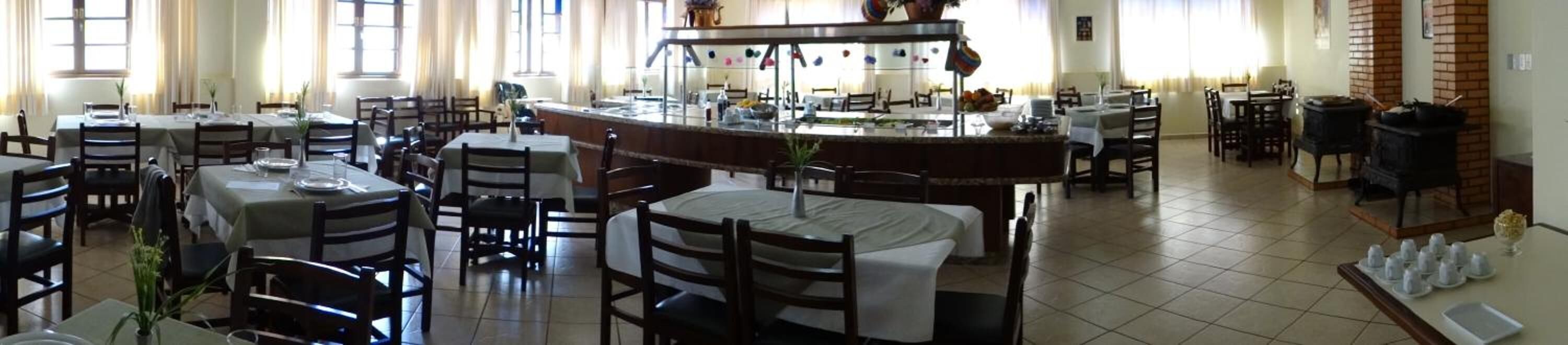 A restaurant with multiple tables and chairs, a central bar area, and a tiled floor.