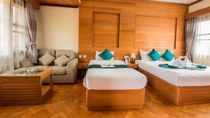 A hotel room with two beds, a sofa, a glass-top table, wooden flooring, and wooden paneling on the walls. - Win Unity Pyin Oo Lwin (Pyin Oo Lwin)