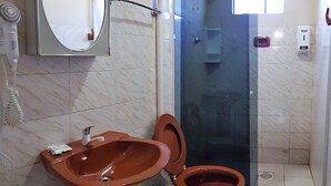 A bathroom with a brown sink, green toilet, and a glass shower enclosure. - Hotel Dal Cortivo (Candiota)