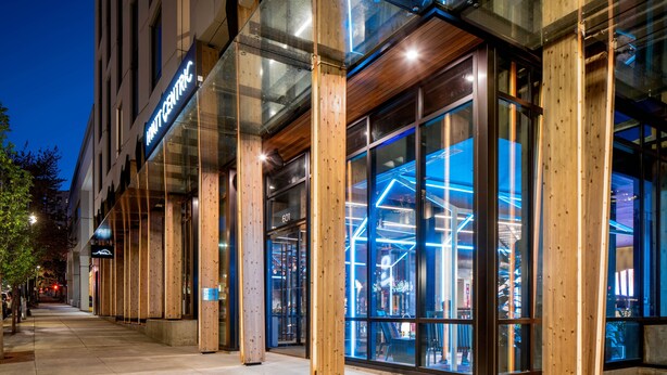 Un edificio moderno con amplios ventanales de vidrio y vigas de madera, con un letrero que dice "HOTEL CENTRE".