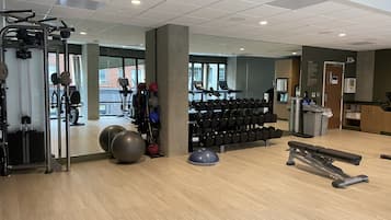 Une salle de sport équipée de matériel d’exercice, de supports pour les poids et de ballons d’exercice.