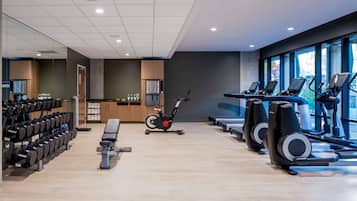A gym with exercise equipment, a bench, and a wall-mounted TV.