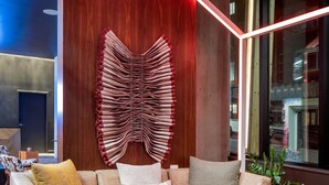 Una sala de estar moderna con un sofá modular, una mesita de centro redonda con una planta y una pieza de arte mural original.