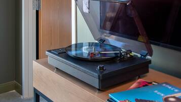 A turntable on a wooden table with a book and a magazine beside it.
