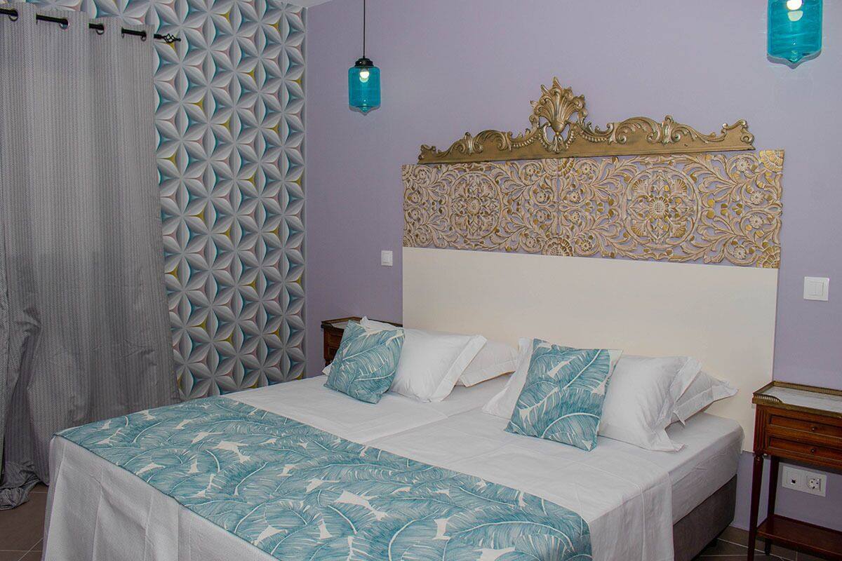 A bedroom with a bed, a headboard with a decorative panel, a nightstand, and a wall with a geometric pattern.