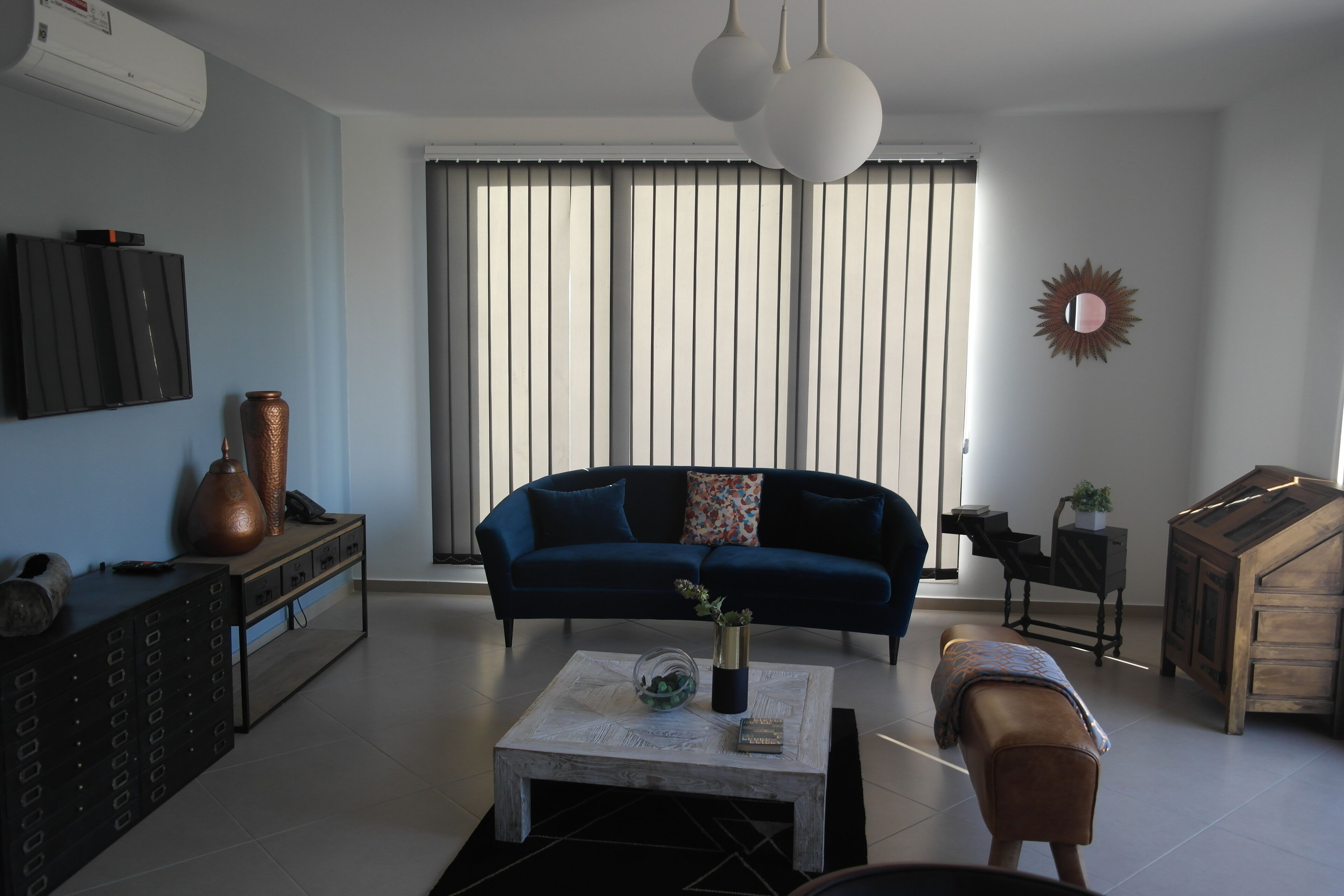 Una sala de estar moderna con un sofá azul, una mesa de centro y un televisor montado en la pared.
