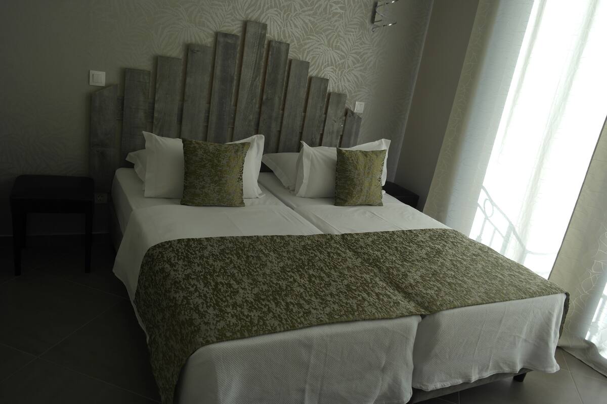A neatly made bed with a patterned throw, a wooden headboard, and a small bedside table.