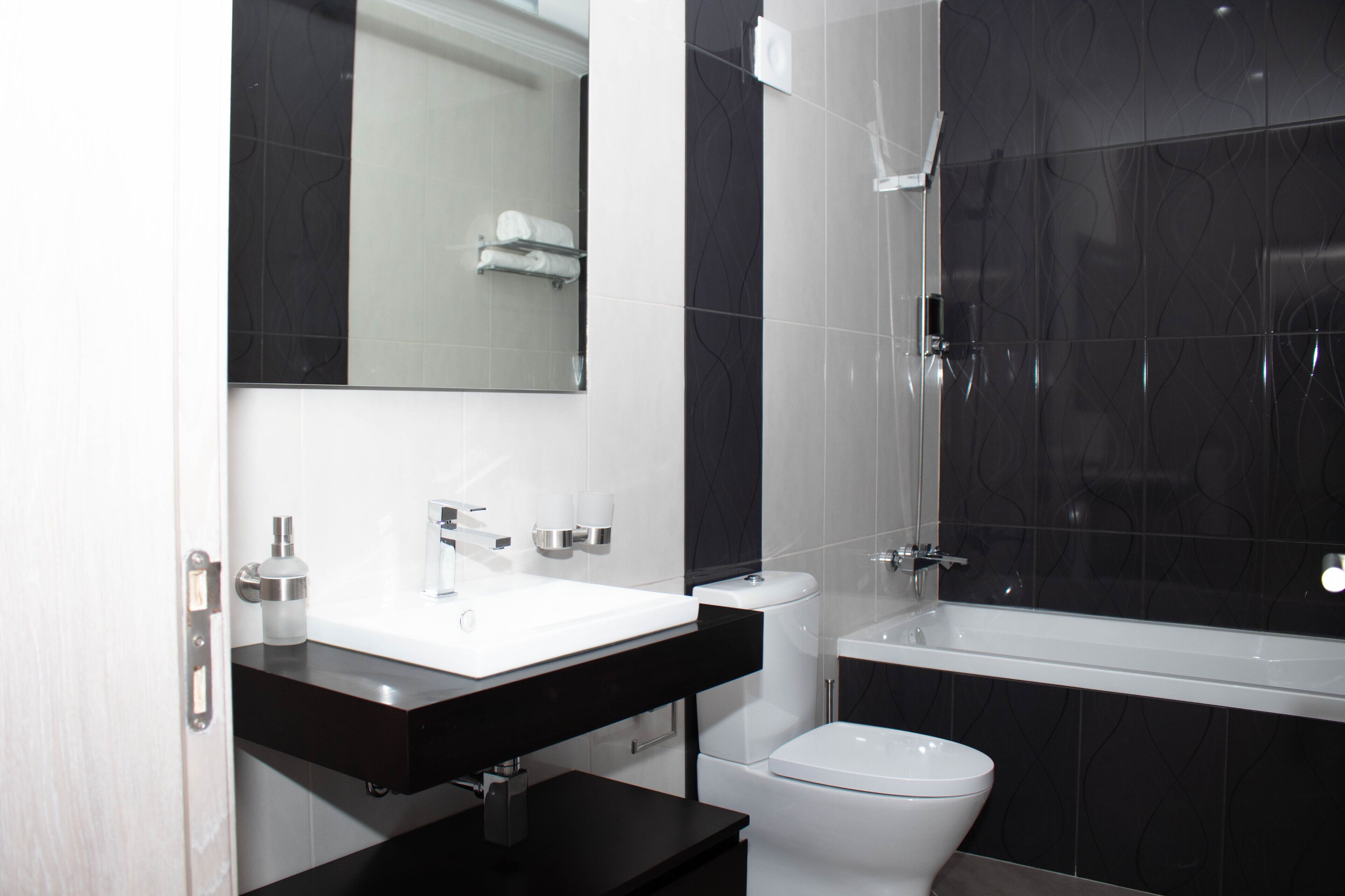 Un baño moderno con lavamanos blanco, encimera negra y bañera.