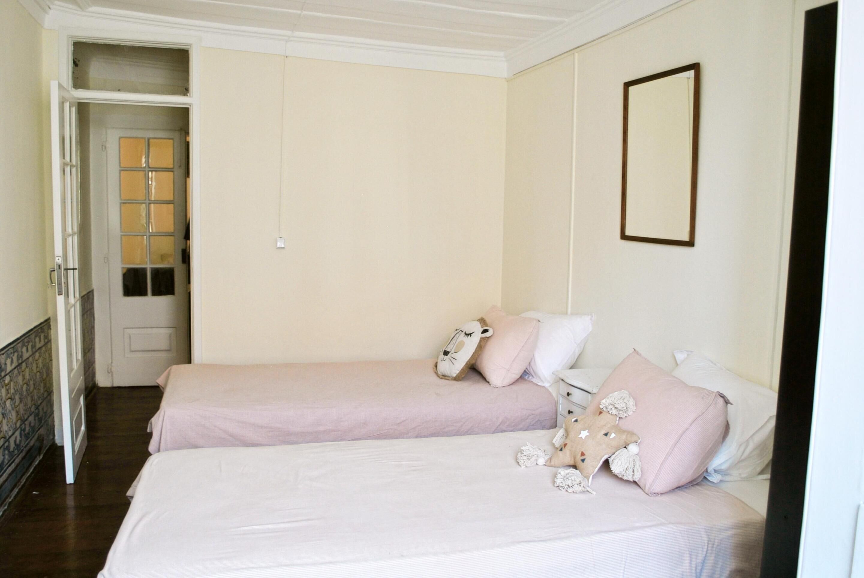 Un dormitorio con dos camas, una puerta y un espejo.